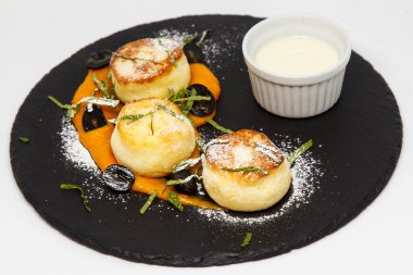 Ekşi krema ve kayısı reçeli pudra şekerli bir tabakta cheesecake.