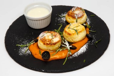 Ekşi krema ve kayısı reçeli pudra şekerli bir tabakta cheesecake.