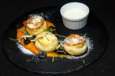 Ekşi krema ve kayısı reçeli pudra şekerli bir tabakta cheesecake.