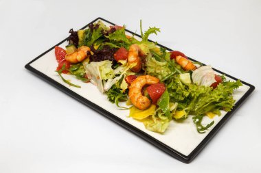 Dikdörtgen bir tabakta karides ve taze sebzeli salata.