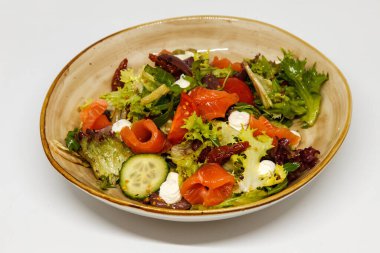 Kırmızı balıklı salata ve el yapımı tabakta taze sebze.