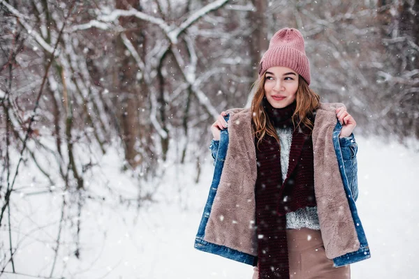 Young girl in unbuttoned jacket stands under snowfall — Stock Photo, Image