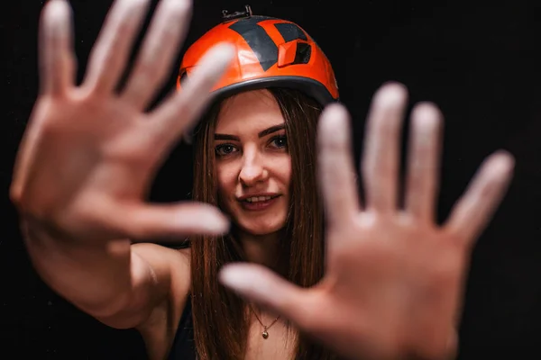 A girl in climbing gear poses against a black background