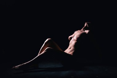 Bir fotoğraf stüdyosundaki siyah arka planda genç, ince bir siluet.