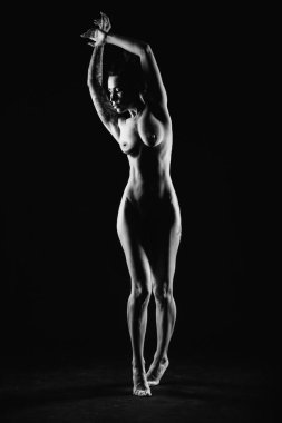 Bir fotoğraf stüdyosundaki siyah arka planda genç, ince bir siluet.