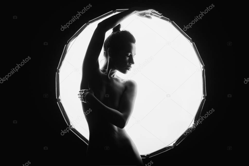 The silhouette of a young, slender, in the light of softbox.