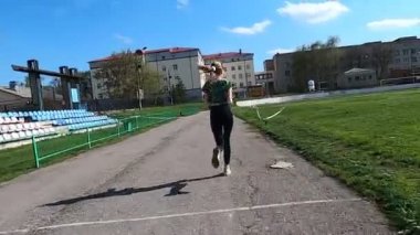 Genç, narin kız stadyumda antrenman yapıyor.