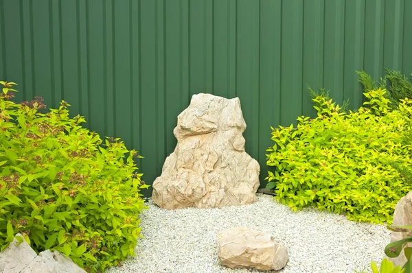 Fragment of the garden with green bushes and bright stones. — Stock Photo, Image