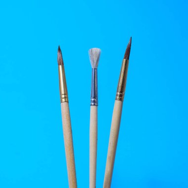 ressamlar için mavi arkaplan araçlarına yakın plan resim yapmak için boya fırçaları