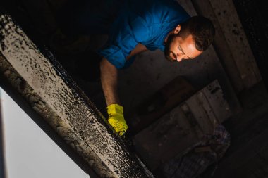 Bir inşaatçı bir kır evinin duvarlarını boyar. Kır evi inşaatı, inşaat hizmetleri.