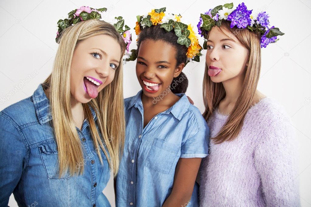 Cute teenage mixed race girls wearing wreath of flowers, studio shoot.