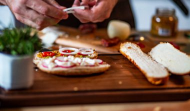 Food concept; Chef decorate fresh homemade hot dog.Young man with tattoo decorate delicious hot dog in a kitchen.
