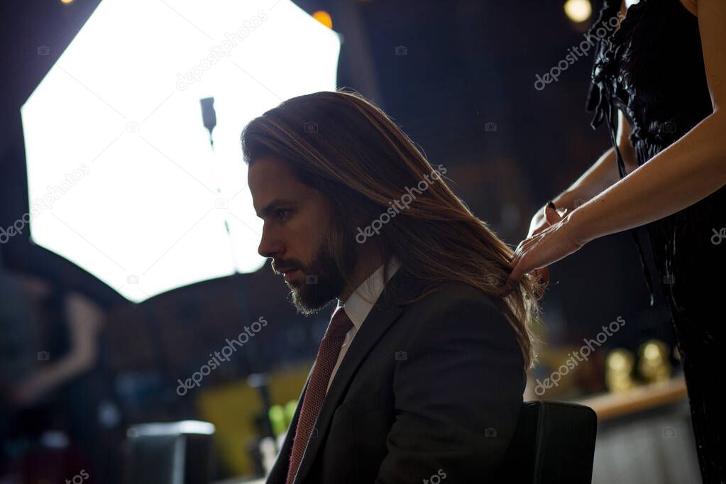 Close up of beautiful mans long straight hair.Hairstylist combing and drying hair to handsome young businessman in a beauty salon.