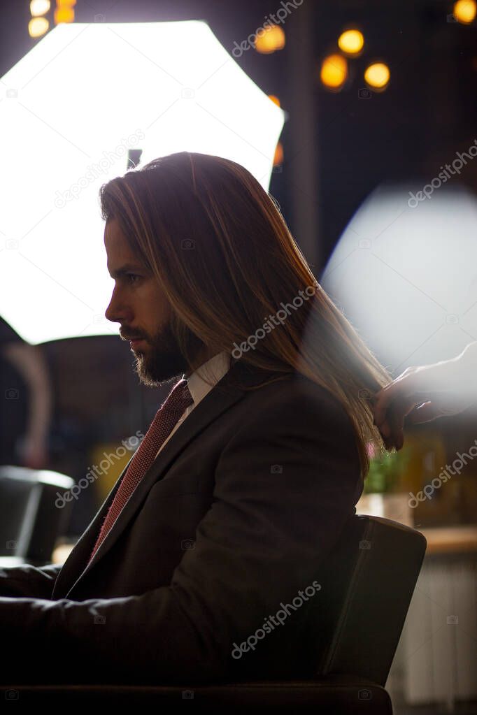 Close up of beautiful mans long straight hair.Hairstylist combing and drying hair to handsome young businessman in a beauty salon.