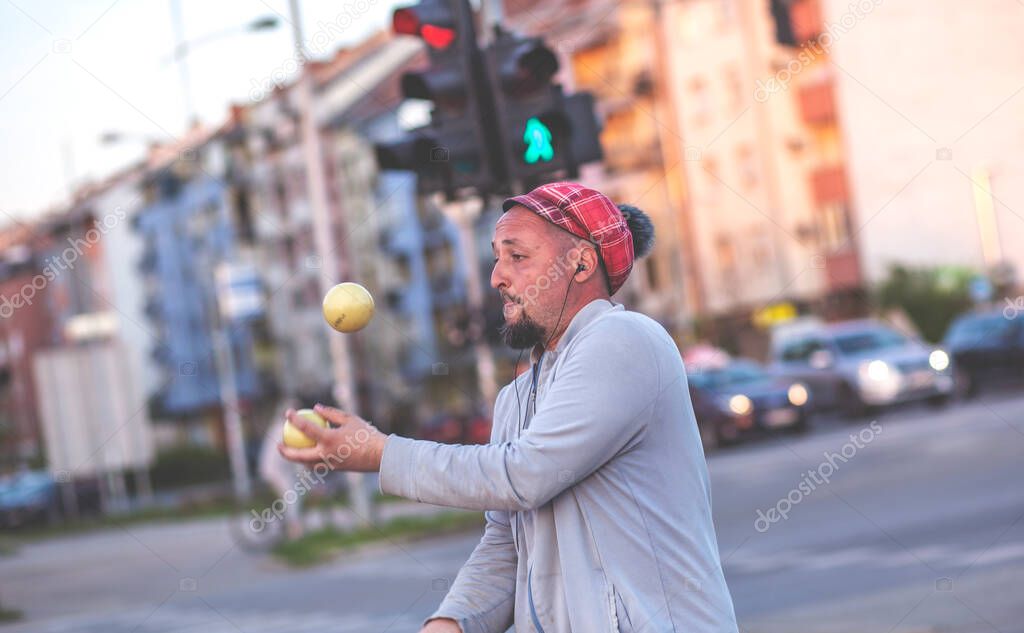A juggler working in traffic. Juggler man performing at the traffic lights, after the presentation he asks the drivers for a donation.
