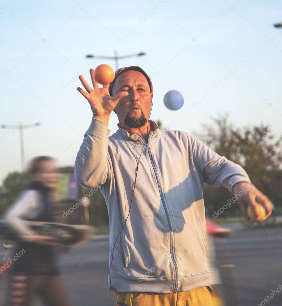 A juggler working in traffic. Juggler man performing at the traffic lights, after the presentation he asks the drivers for a donation.