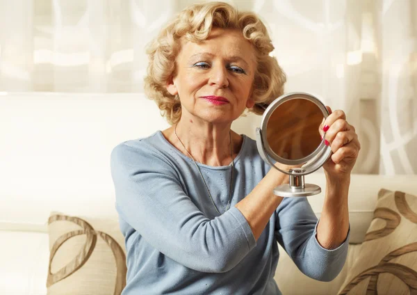 Lächelnde ältere Frau kämmt und blickte in den Spiegel — Stockfoto