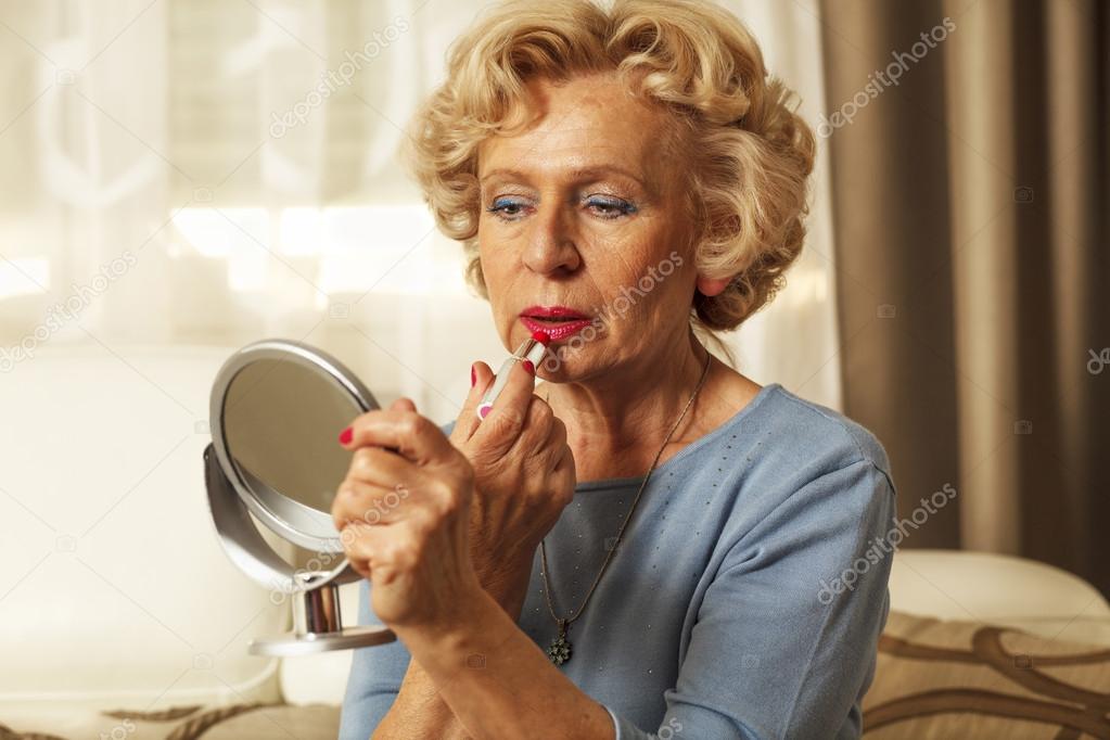 Elderly woman applied lipstick and looked in the mirror