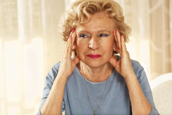 Blonde senior woman has a headache. — Stock Photo, Image