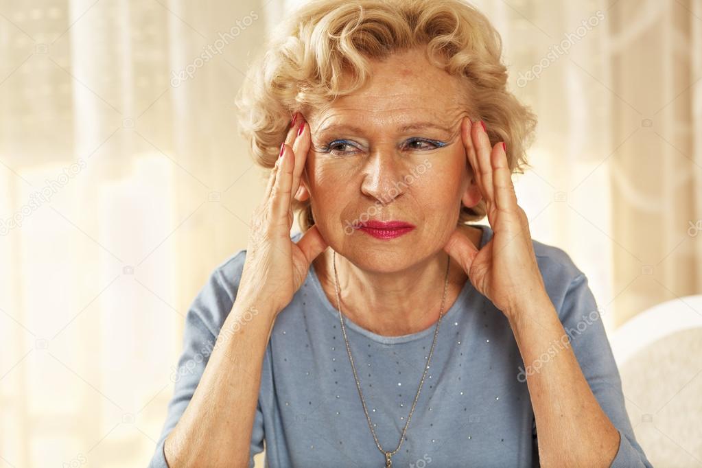 Blonde senior woman has a headache.