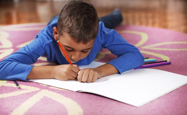 Young mixed race boy drawing on paper with crayon. — Stock Photo, Image
