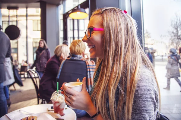 Jong blond meisje drinken koffie in cafe. — Stockfoto