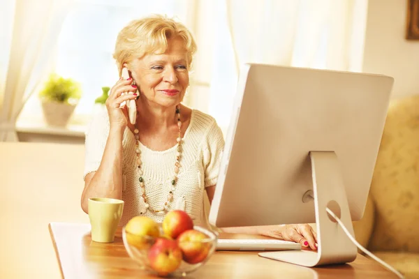 Blonde bejaarde vrouw chatten op een mobiele — Stockfoto