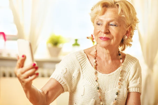 Elderly woman  taking photo of herself with smart phone — Stock Photo, Image