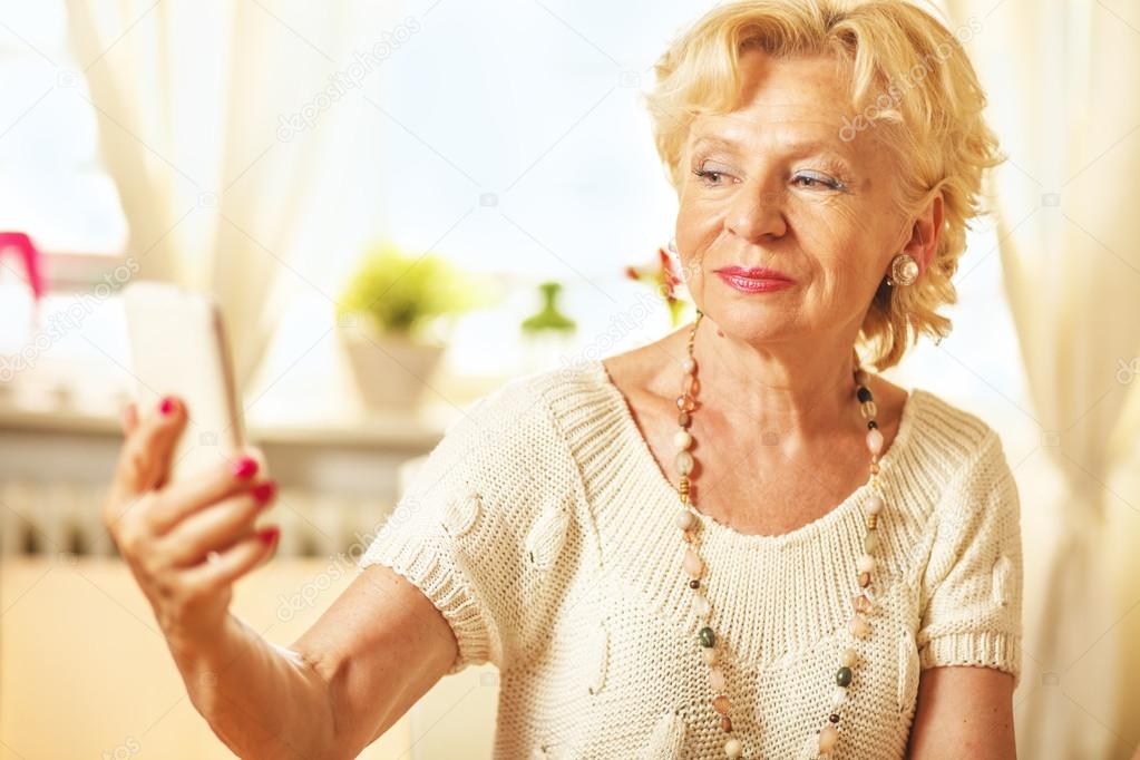Elderly woman  taking photo of herself with smart phone