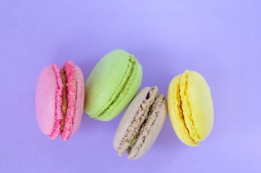 Dört renkli kurabiyenin üst görüntüsü, mor arka planda, fotokopi alanı ile yan yana. Geleneksel Fransız pastası.