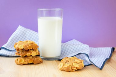 Mısır gevreği, kuru üzüm ve menekşe arkaplanda bir bardak sütle birlikte taze pişmiş bisküviler. Sağlıklı atıştırmalık ve lezzetli kahvaltı kavramı.