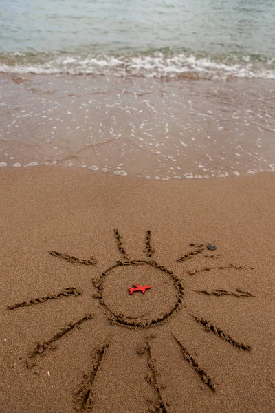 figure of a red plane and painted the sun on the sand on the coast. rest and tourism by plane to the sea. A picture of the sun and the symbol of the plane by the sea.