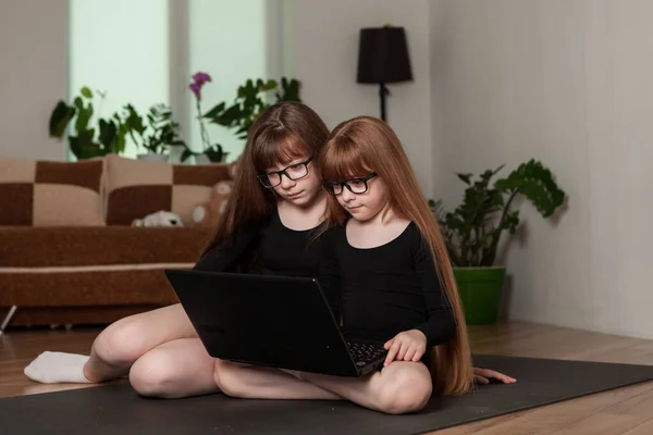 little girls, sisters hold an online lesson, gymnastics at home.
