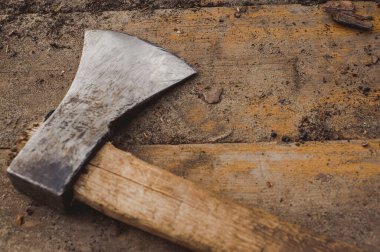 Kaba ahşap tahtaların üzerinde duran baltayla. Ahşap işçiliği, ormancılık ve el işçiliği için kullanılan geleneksel el aleti, kırsal ve doğal karakterli.