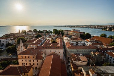 Çan kulesinden Zadar 'ın kırmızı kiremitli çatıları ve Adriyatik Denizi' ni gören yüksek perspektifli panoramik manzarası. Tarihi mimarisi ve kıyı ufkuyla seyahat yeri şehir manzarası.