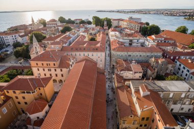Çan kulesinden Zadar 'ın kırmızı kiremitli çatıları ve Adriyatik Denizi' ni gören yüksek perspektifli panoramik manzarası. Tarihi mimarisi ve kıyı ufkuyla seyahat yeri şehir manzarası.