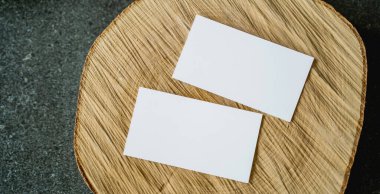Boş kartvizitler, yumuşak ışık ve sığ alan derinliğiyle doğal ahşap bir yüzeye yerleştirilmiş. Markalaşma, kimlik tasarımı ve kurumsal sunum için temiz bir model.
