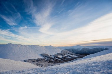 Karlı tepeler ve soğuk yürüyüş koşulları sırasında Tarnica 'dan görülen Bieszczady Dağları' nın uzak tepeleri ile mavi saat gündoğumu sırasında dağ manzarası.