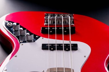 Telleri, köprüyü ve pikapları gösteren dört telli kırmızı bir bas gitarın yakın plan detayları. Müzik aleti arkaplanı.