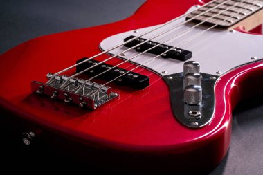 Telleri, köprüyü ve pikapları gösteren dört telli kırmızı bir bas gitarın yakın plan detayları. Müzik aleti arkaplanı.