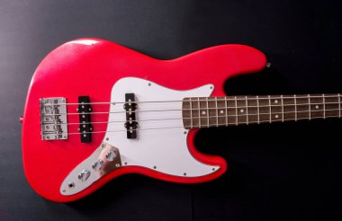 Telleri, köprüyü ve pikapları gösteren dört telli kırmızı bir bas gitarın yakın plan detayları. Müzik aleti arkaplanı.