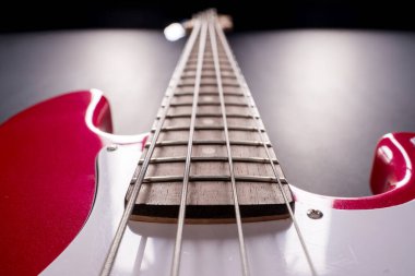 Telleri, köprüyü ve pikapları gösteren dört telli kırmızı bir bas gitarın yakın plan detayları. Müzik aleti arkaplanı.