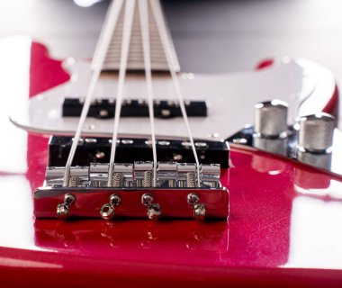 Telleri, köprüyü ve pikapları gösteren dört telli kırmızı bir bas gitarın yakın plan detayları. Müzik aleti arkaplanı.