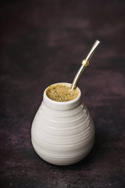 Yerba mat ve metal bombilla ile dolu seramik materyal kasvetli bir yaşam kompozisyonu koyu dokulu bir yüzey üzerine yerleştirilir.