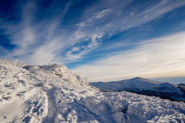 Mavi gökyüzü, altın saat ışığı ve panoramik dağ manzarası ile soğuk bir kış sabahı Bieszczady 'de kar yamaçlarını kapladı..