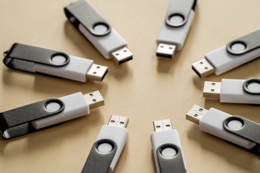 Nötr bej bir yüzeyde dairesel bir bileşime yerleştirilmiş çoklu USB flash diskler taşınabilir veri depolama ve dijital teknolojiyi temsil ediyor..