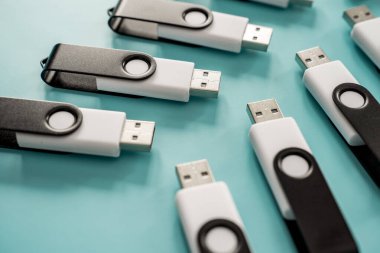 Portatif veri depolama ve dijital teknolojiyi temsil eden turkuaz bir yüzeye yerleştirilmiş çoklu siyah beyaz USB flash diskler.