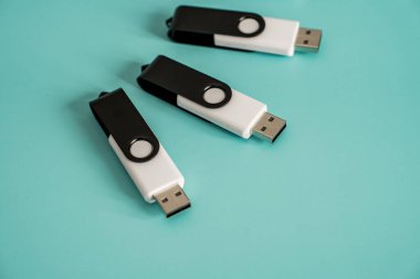 Portatif veri depolama ve dijital teknolojiyi temsil eden turkuaz bir yüzeye yerleştirilmiş çoklu siyah beyaz USB flash diskler.