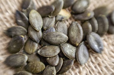 Çuval bezine doğal kabak tohumları yakın çekim. Sağlıklı atıştırmalık konsepti, bitki temelli beslenme ve organik gıda dokusu.