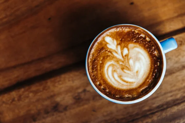 Cappuccino i blå mugg på ett träbord. Kaffevy ovanifrån Stockbild
